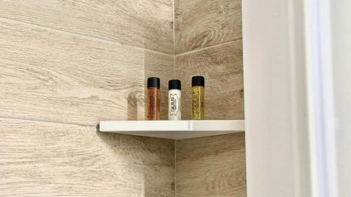a shelf with three cosmetics on it in a bathroom at Le Saline Rooms Marzamemi in Marzamemi