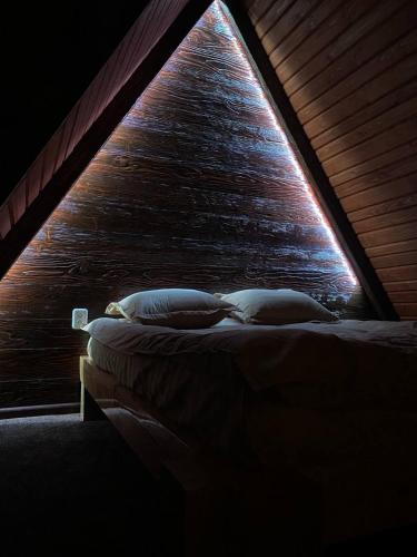 a bed in a room with a wooden wall at Котедж A-frame Strimba in Verkhnyaya Rozhanka