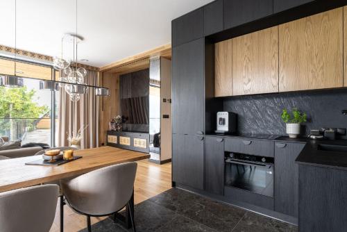 a kitchen with black cabinets and a wooden table at Osada Gubałówka na Polanie Pająkówka & SPA in Kościelisko