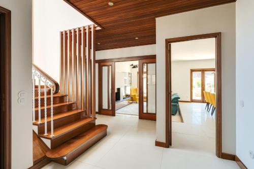 a hallway with wooden stairs and a living room at Beach Villa with Jacuzzi & Garage by HostWise in Vila Chã