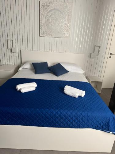 a blue and white bed with two towels on it at Le Saline Rooms Marzamemi in Marzamemi
