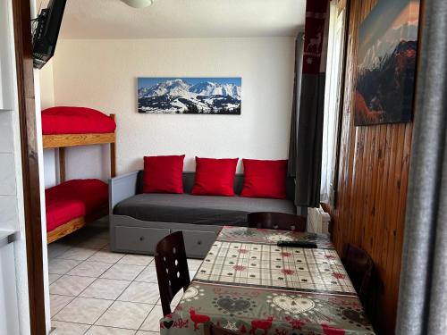 a room with a bed with red pillows and a table at APPARTEMENT BICHE in La Llagonne