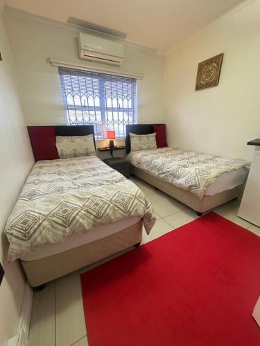 two beds in a room with a red rug at Surrey B&B in Surrey Estate