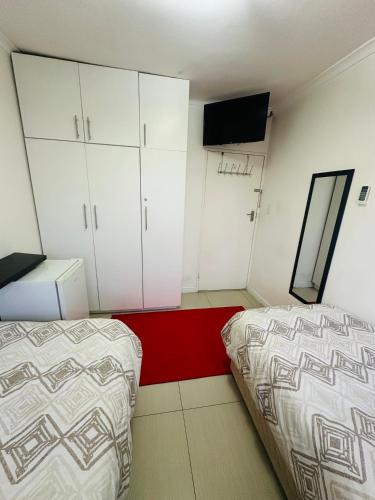 a bedroom with two beds and cabinets and a television at Surrey B&B in Surrey Estate