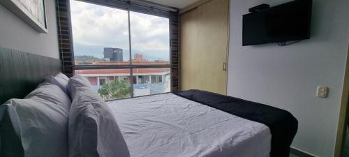 a bedroom with a bed and a large window at La 70, Laureles Condo, Cold AC in Medellín