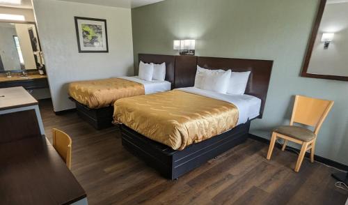 a hotel room with two beds and a table and chairs at Quality Inn Moss Point - Pascagoula in Moss Point