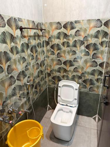 a bathroom with a toilet and a flower patterned wall at OM LINGESWARAN HOME STAY Tiruvannamalai in Tiruvannāmalai