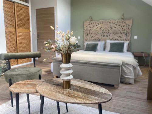 una camera da letto con un letto e un vaso di fiori su un tavolo di Gîte dans moulin - Chic et Charme - Piscine et Spa a Rouessé-Vassé