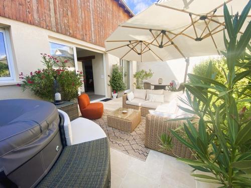 patio con divano e ombrellone di Gîte dans moulin - Chic et Charme - Piscine et Spa a Rouessé-Vassé