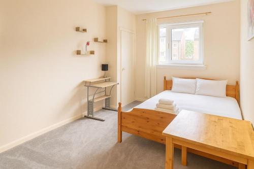 a bedroom with a bed and a wooden table at Bright & Spacious 2 Bedroom Flat in Edinburgh