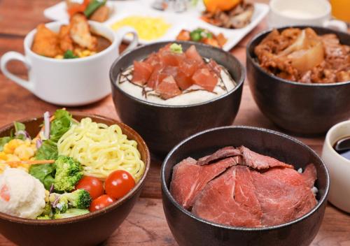 a table topped with bowls of different types of food at APA Hotel TKP Sapporo Eki-Kitaguchi Excellent in Sapporo