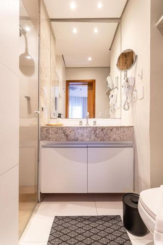 a white bathroom with a sink and a mirror at Flat Parque do Ibirapuera - Jardins in Sao Paulo