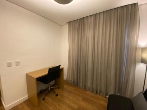 a room with a desk and a window with a curtain at Flat Parque do Ibirapuera - Jardins in Sao Paulo