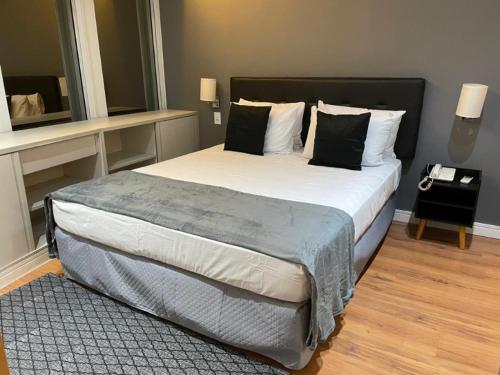 a bedroom with a large bed with black and white pillows at Flat Parque do Ibirapuera - Jardins in Sao Paulo