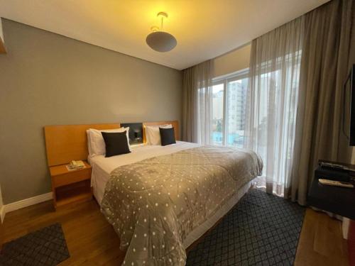 a hotel room with a bed and a large window at Flat Parque do Ibirapuera - Jardins in Sao Paulo