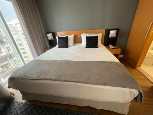 a large bed in a room with a large window at Flat Parque do Ibirapuera - Jardins in Sao Paulo