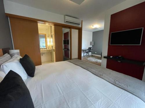 a bedroom with a large bed with a flat screen tv at Flat Parque do Ibirapuera - Jardins in Sao Paulo