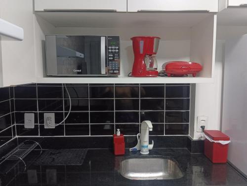 eine Küchentheke mit Spüle und Mikrowelle in der Unterkunft Flat com piscina em Tambaú in João Pessoa