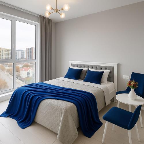a white bedroom with a blue and white bed and a window at Зелена тераса in Lviv