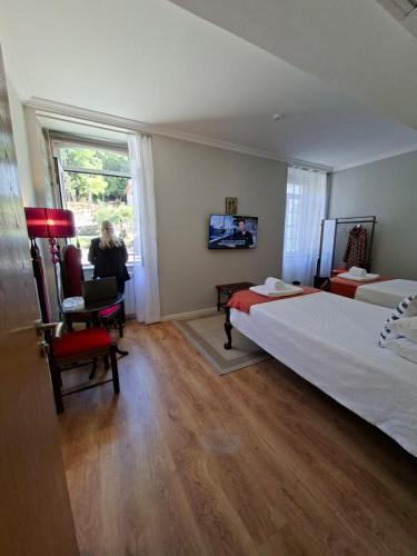a bedroom with a large bed and a woman sitting in a chair at Quinta de Marzovelos in Viseu