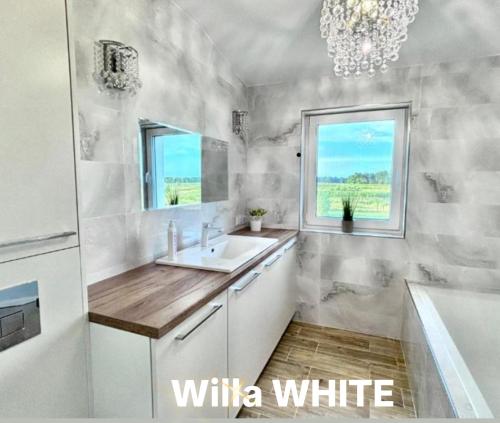 a bathroom with a sink and a tub and a window at Dom Michałki Luksusowa willa z ogrodem in Michalki