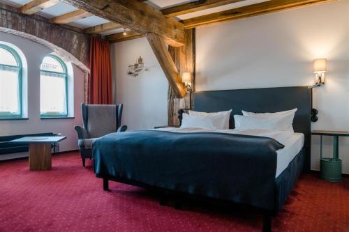 a hotel room with a bed and a table and chairs at Elbe Resort Alte Ölmühle in Wittenberge