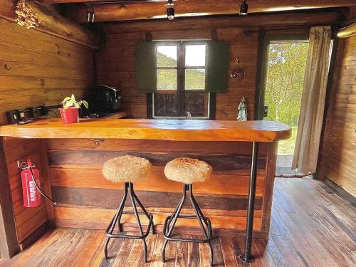 Una cocina con una encimera de madera con dos taburetes. en Gaia Cabanas - Urubici - Terra, en Mundo Novo
