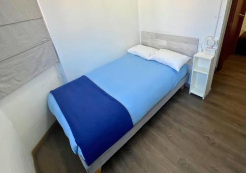 a small bedroom with a blue bed and a night stand at The Hostel Santiago in Santiago