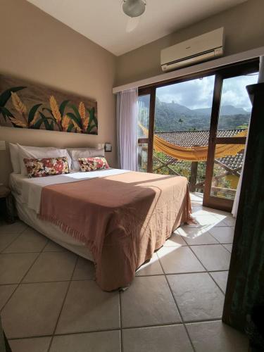 a bedroom with a large bed and a large window at Pousada Caiçara in Abraão