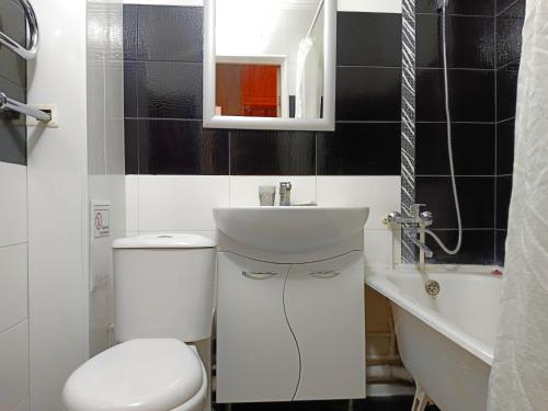 a bathroom with a white toilet and a sink at Nectar Apartments in Aktobe