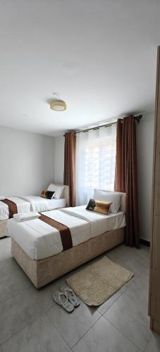 a bedroom with two beds and a window at Perfect palm Condos-Kings Sapphire in Nakuru