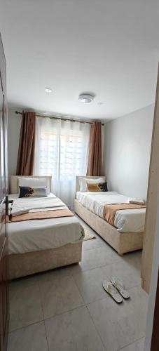 two beds sitting in a room with at Perfect palm Condos-Kings Sapphire in Nakuru