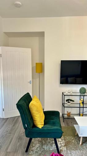 a green couch with a yellow pillow in a living room at Jarrow Contractor & professional accommodation, Near port & hospital, 3bedroom apartment near Newcastle, free parking in Jarrow