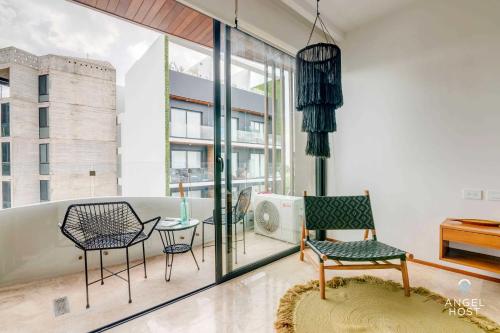 un soggiorno con sedie, tavolo e finestre di Adorable Rooftop Pool, Reliable WiFi, Near 5th Ave a Playa del Carmen