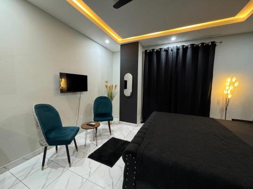a bedroom with a bed and two chairs and a television at Furnished Apartment Islamabad in Islamabad