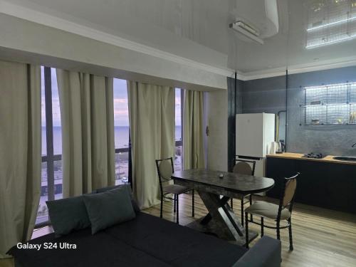 a living room with a table and chairs and a kitchen at Квартира in Aktau