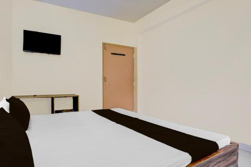 a bedroom with a white bed and a television at HOTEL O SOURYA RESIDENCY in Sānkchi
