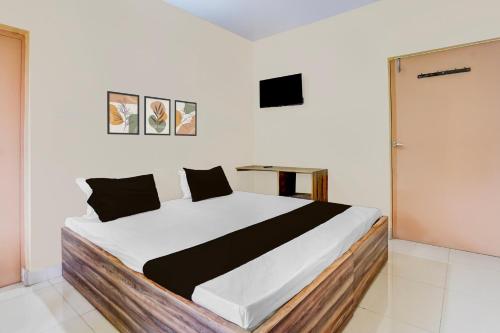 a bedroom with a large white bed with black pillows at HOTEL O SOURYA RESIDENCY in Sānkchi