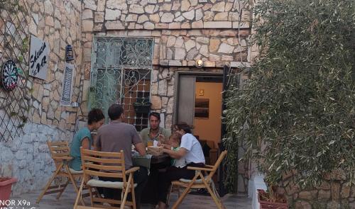 a group of people sitting at a table in front of a building at Seleucia DaR Umm Qais in Um Qeis