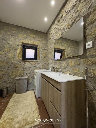 a bathroom with a sink and a stone wall at Quinta Dos Sonhos in Vale de Cambra