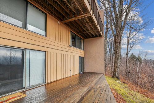 a house with a wooden deck next to a building at Notchbrook 5 Apt. in Stowe