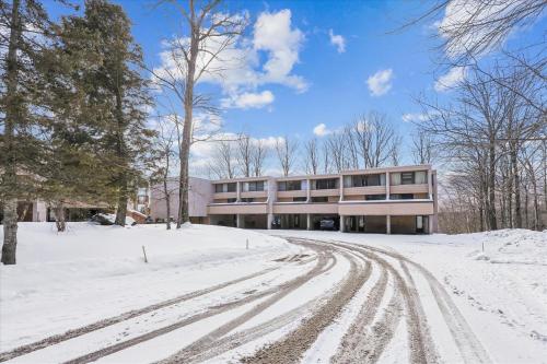 a building in the snow with tracks in the snow at Notchbrook 5 Apt. in Stowe