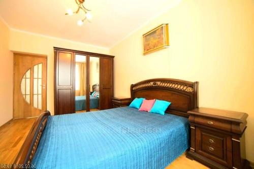 a bedroom with a large wooden bed with blue sheets at Санта Барбара in Lviv