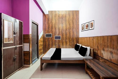 een slaapkamer met een bed en een houten wand bij Hotel O Pushpanjali in Haldwani