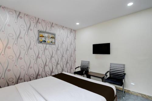 a bedroom with a bed and two chairs and a tv at Hotel O The Pramaan in Kukatpalli
