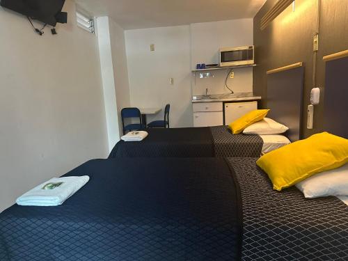 two beds in a small room with a kitchen at Hotel Vagabundo Expo Guadalajara in Guadalajara
