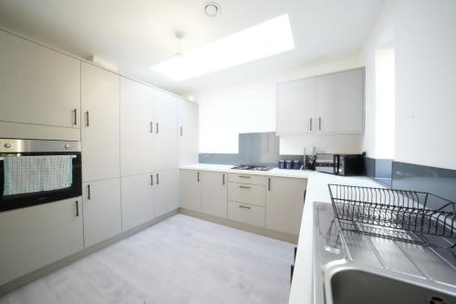a white kitchen with white cabinets and a sink at Ealing Broadway Great Stay 7-Minute Walk from the Underground in Ealing