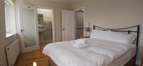 a bedroom with a white bed with towels on it at Beautiful 3BD Home Beside Phoenix Park in Dublin