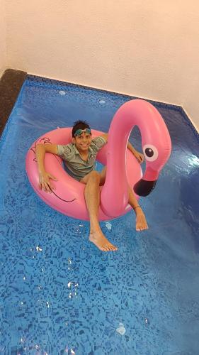 a man in a pink flamingo in a swimming pool at The Royal Ascot Holiday Home in Alibaug