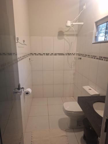 ein Badezimmer mit Dusche, Toilette und Waschbecken in der Unterkunft Suítes Recanto das Flores 3 in Pirenópolis